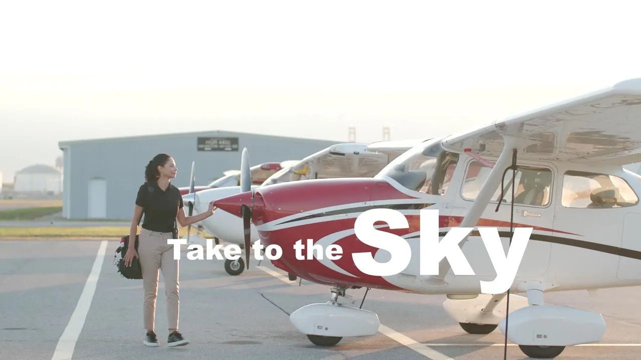 On-camera talent standing beside a training aircraft at Peter O. Knight Airport during the Elevation brand film shoot